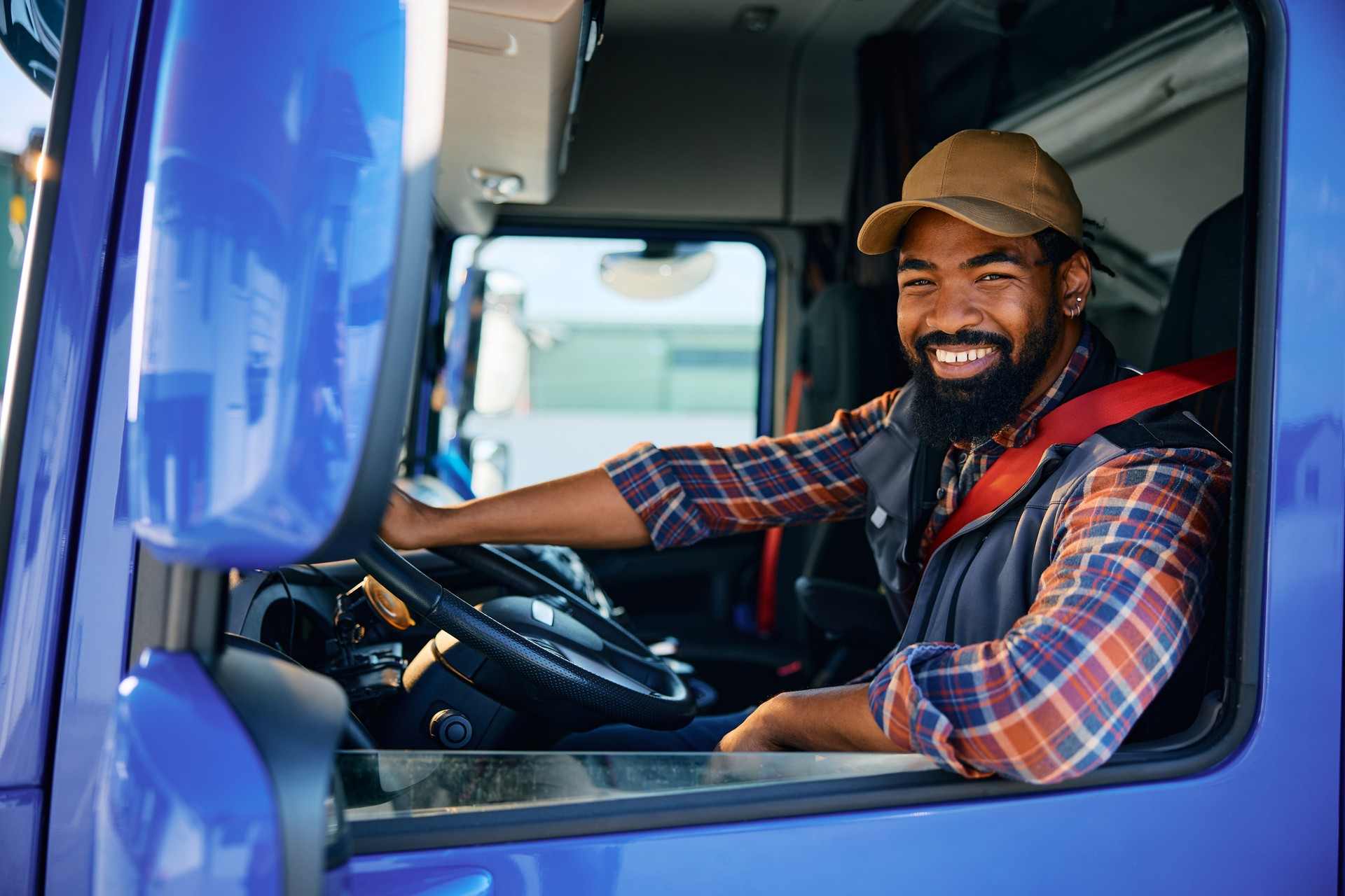 Happy black truck driver behind steering wheel in a cabin smiling because he got paid